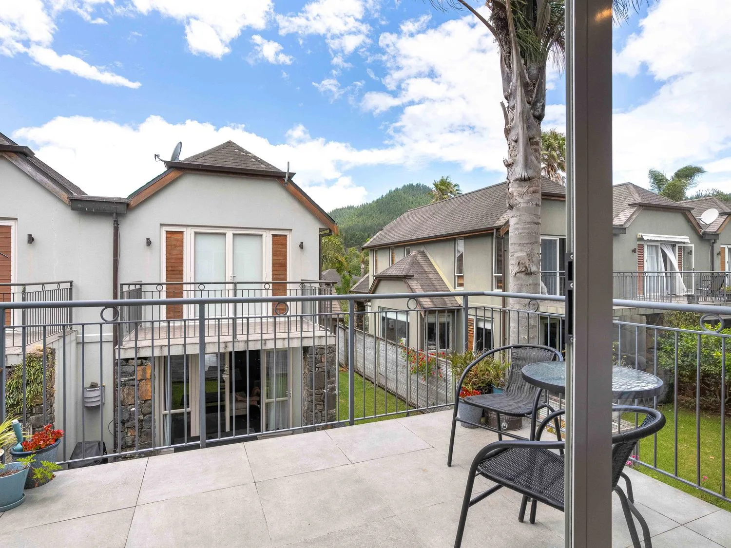 Un balcón con una mesa y sillas con vistas a edificios en Sue's Holiday Home - Pauanui