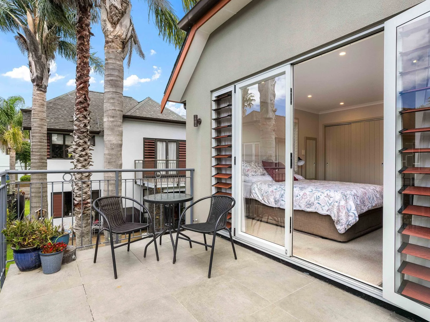 Un dormitorio con balcón y muebles de exterior en Sue's Holiday Home - Pauanui