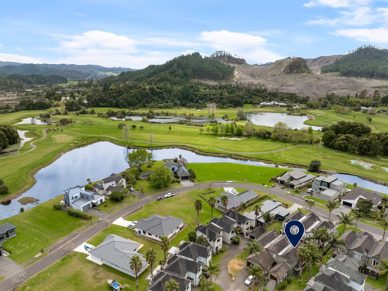 Una vista aérea de viviendas y un campo de golf con lagos y colinas en Sue's Holiday Home - Pauanui Holiday Home Pauanui