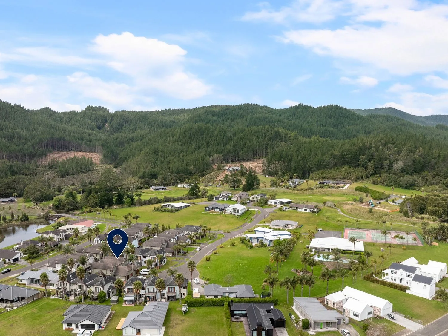 Una vista de casas y montañas con una pista de tenis en Sue's Holiday Home - Pauanui Holiday Home
