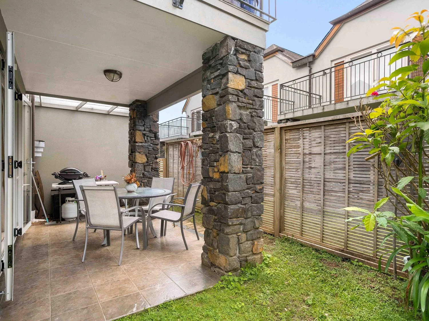 Un patio exterior con mesa y sillas en Sue's Holiday Home - Pauanui Holiday Home, Pauanui