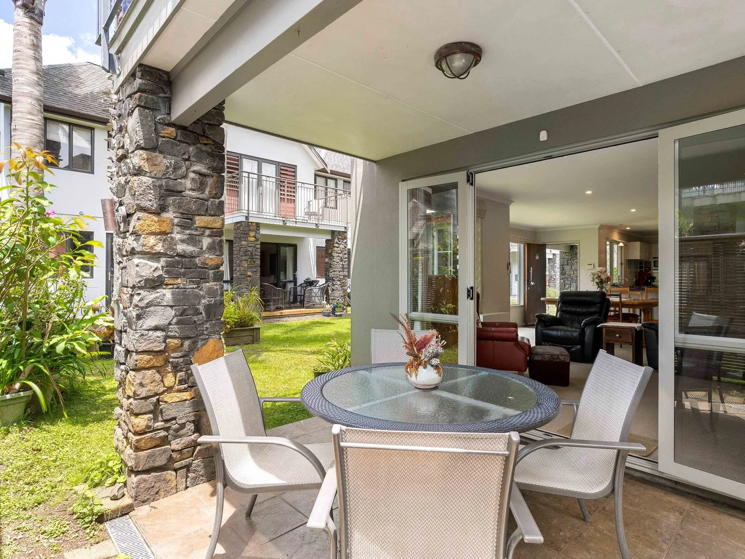 Un patio con una mesa y sillas en Sue's Holiday Home - Pauanui