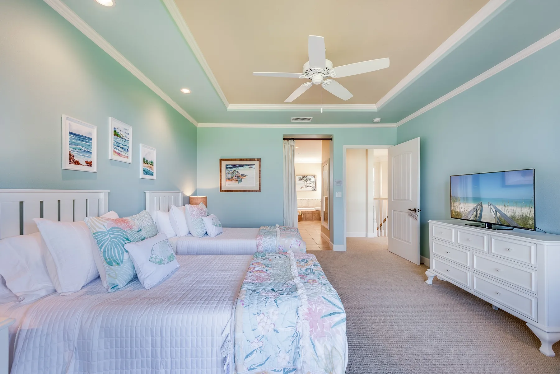 A bedroom with a bed, pale green walls, and a television on a dresser.