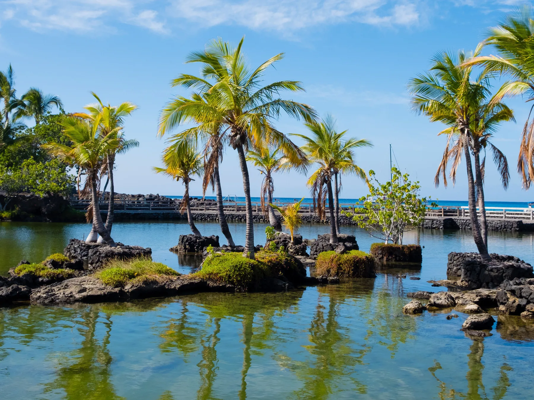A tropical lagoon with palm trees on small rocky islands.