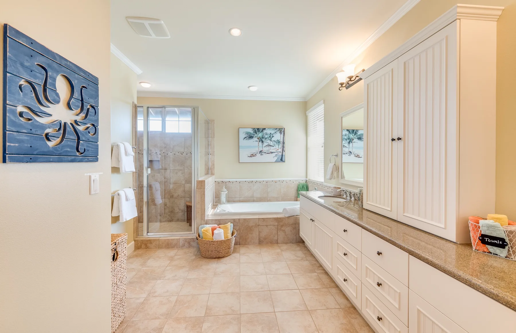 A bathroom with a bathtub, glass shower, and long vanity.