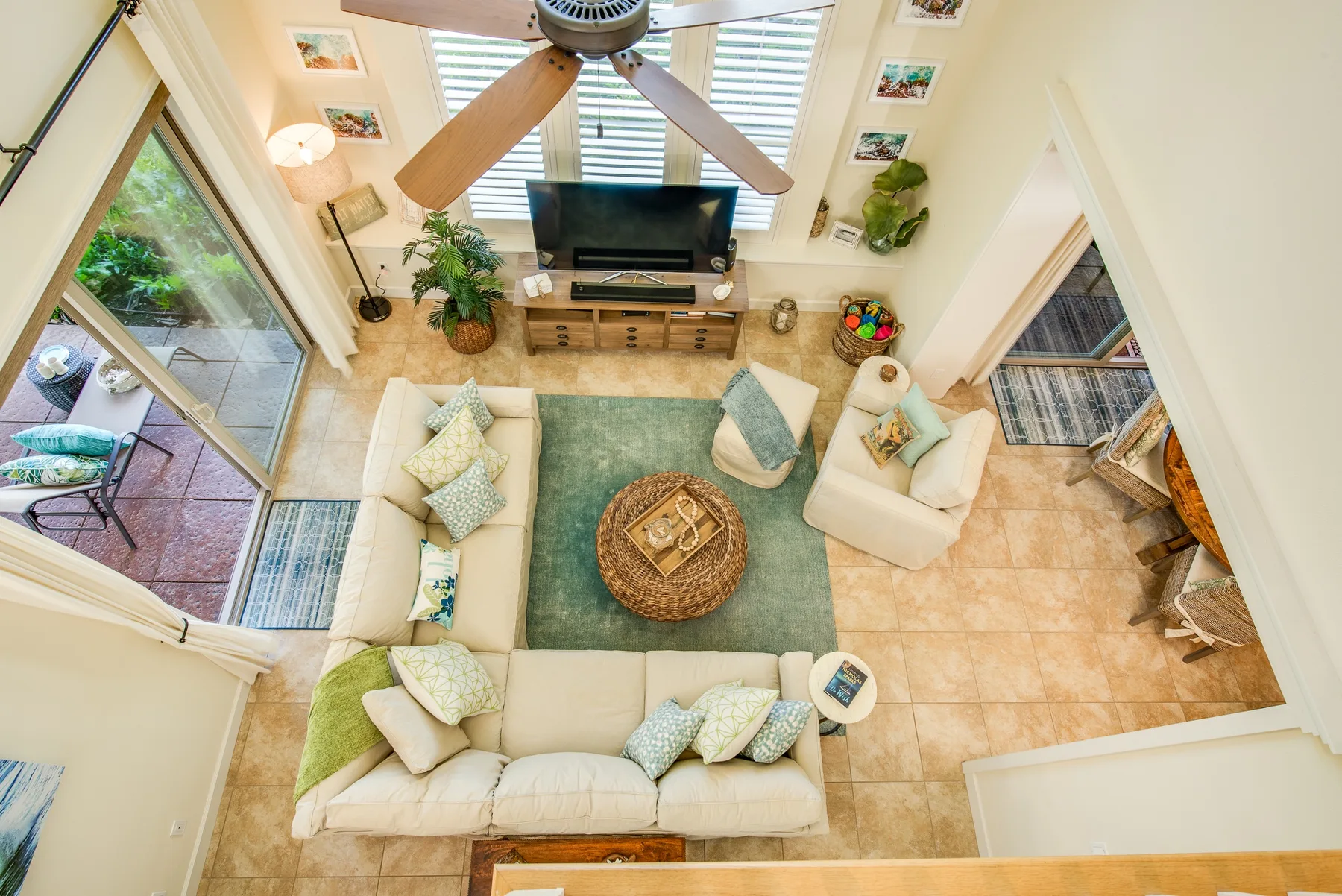 A bright living room with seating around a rug and a television.