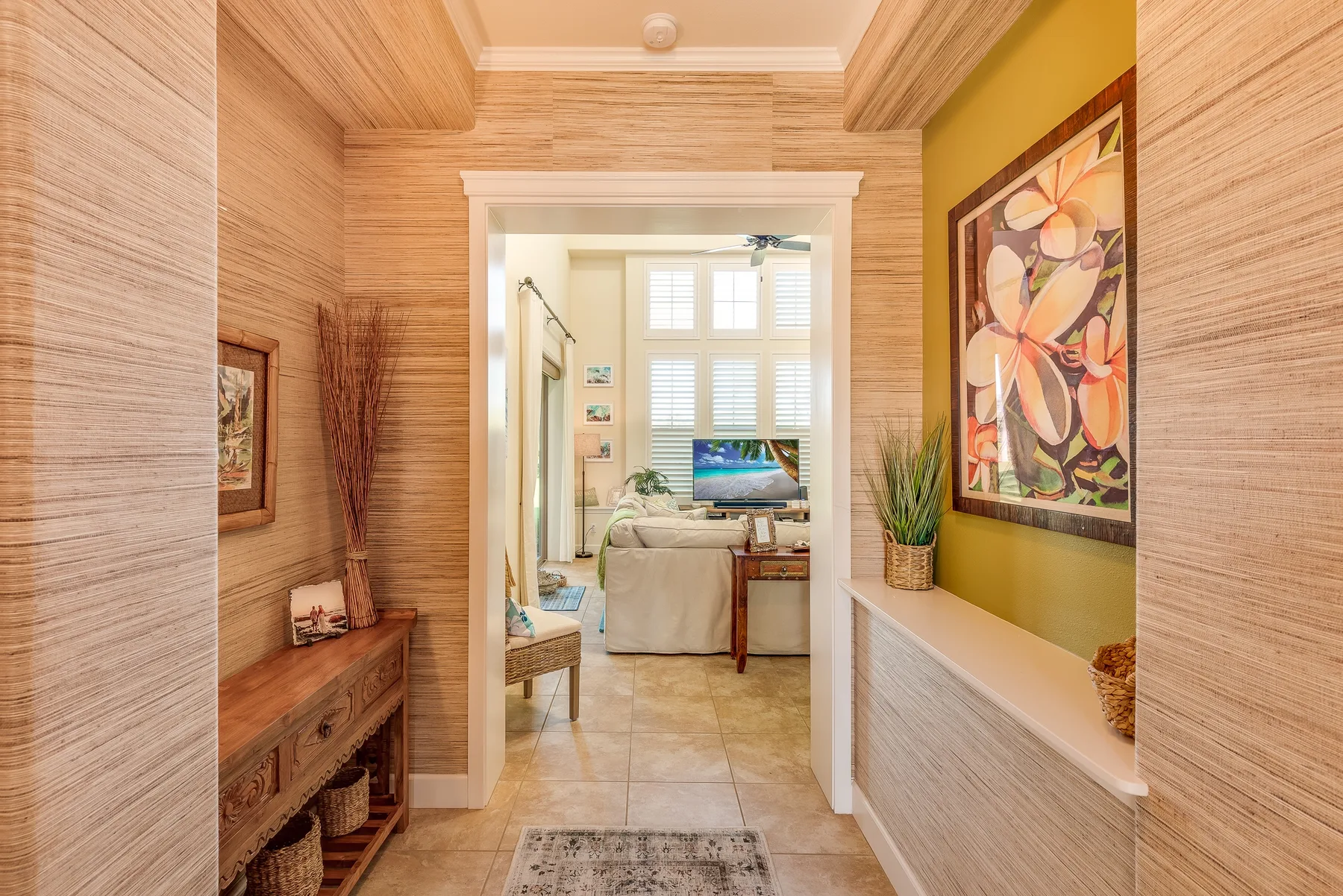 A tiled hallway opens into a bright living room with seating and a television.