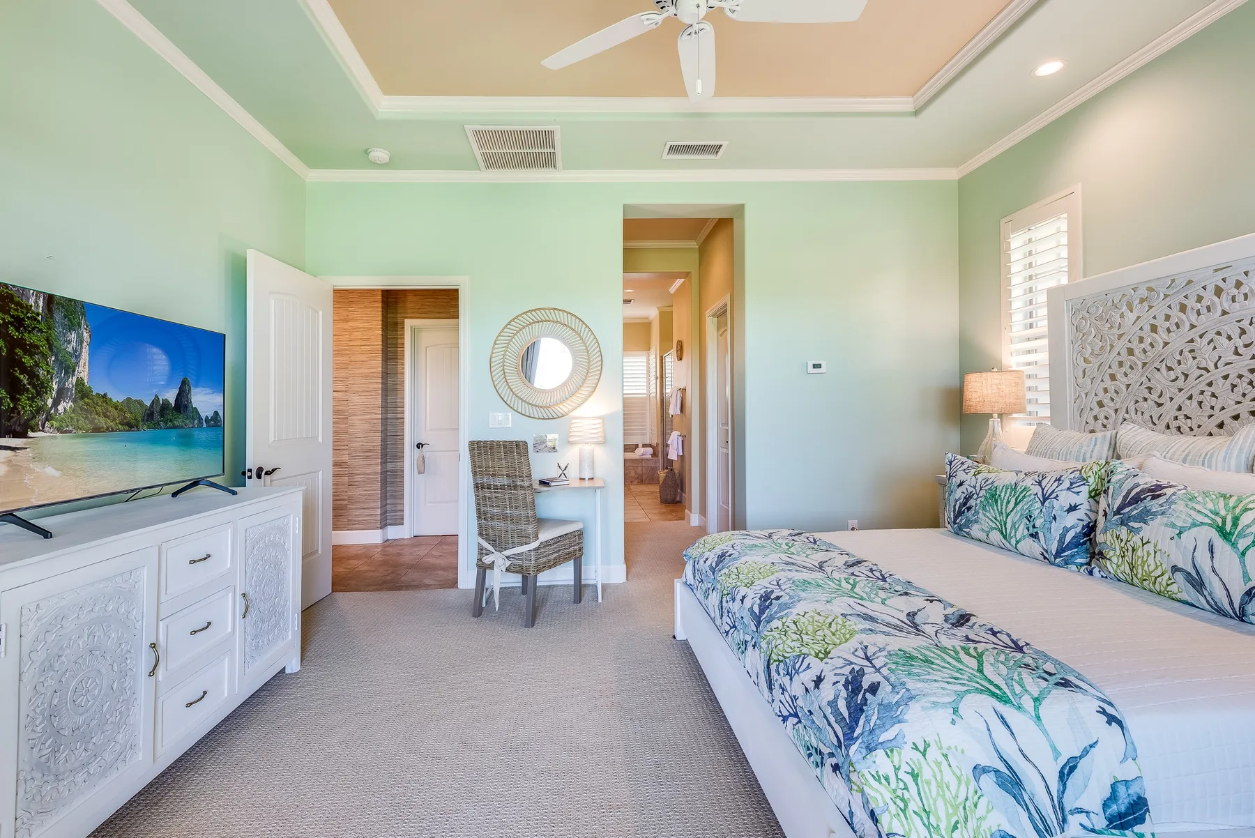 A bedroom with a bed, patterned bedding, and a television on a dresser.