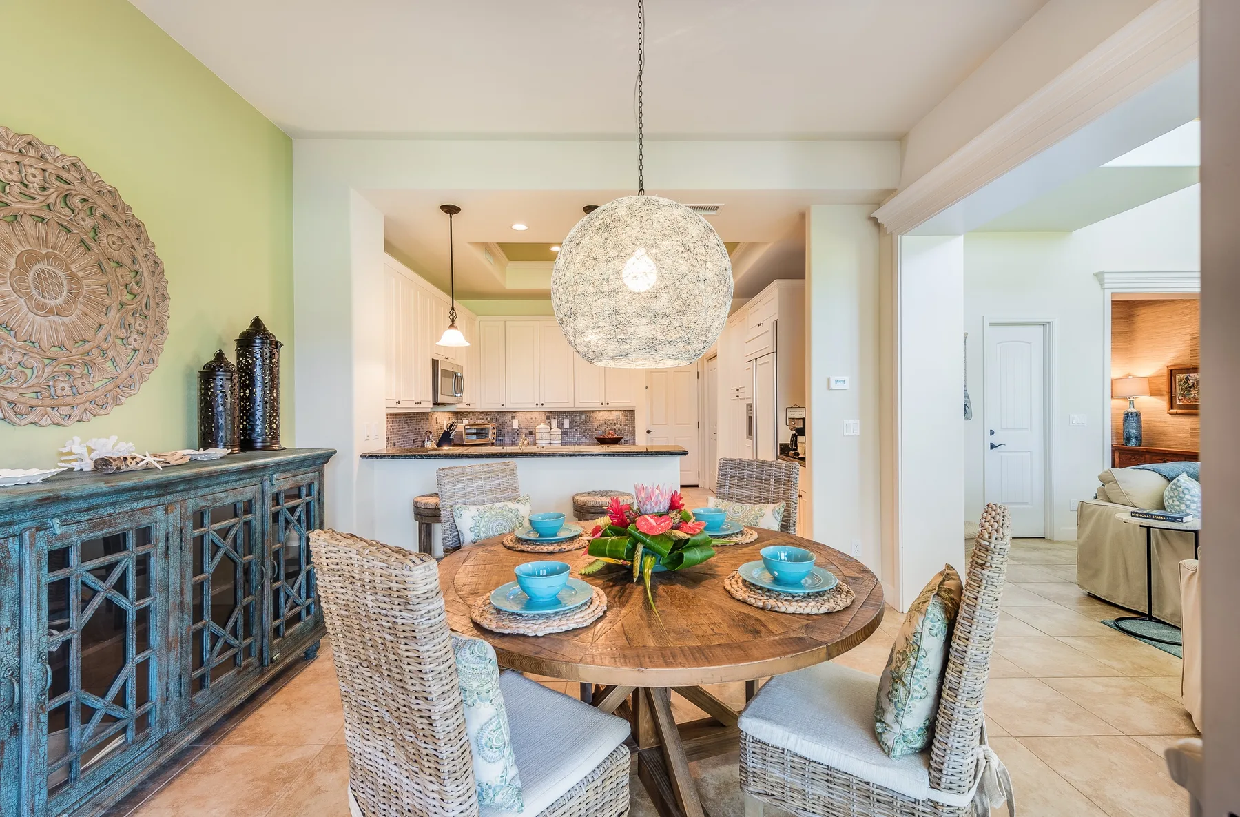 An open dining area with a round table beside a bright kitchen.
