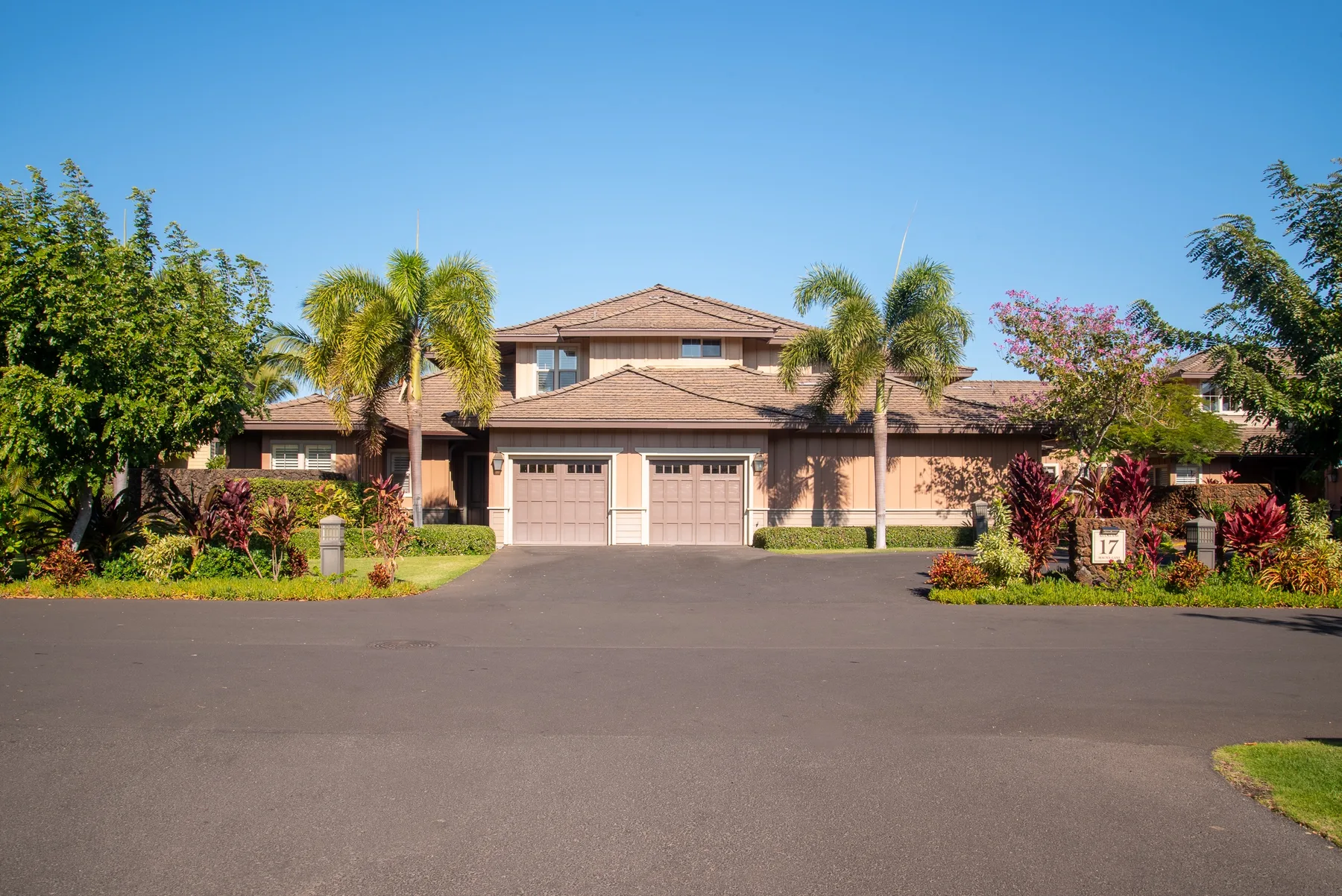 A large house with a tiled roof stands behind a broad paved driveway.
