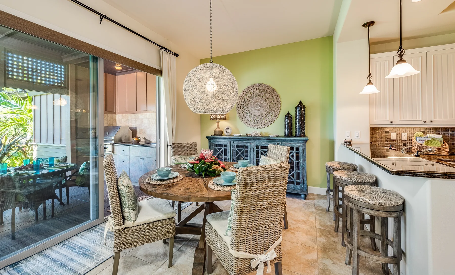 A dining area with a round table and woven seating beside a kitchen counter.