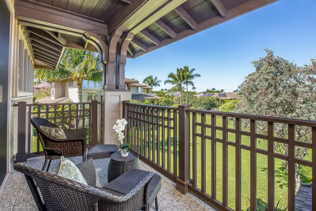 A covered outdoor seating area overlooks a green lawn and palm trees.