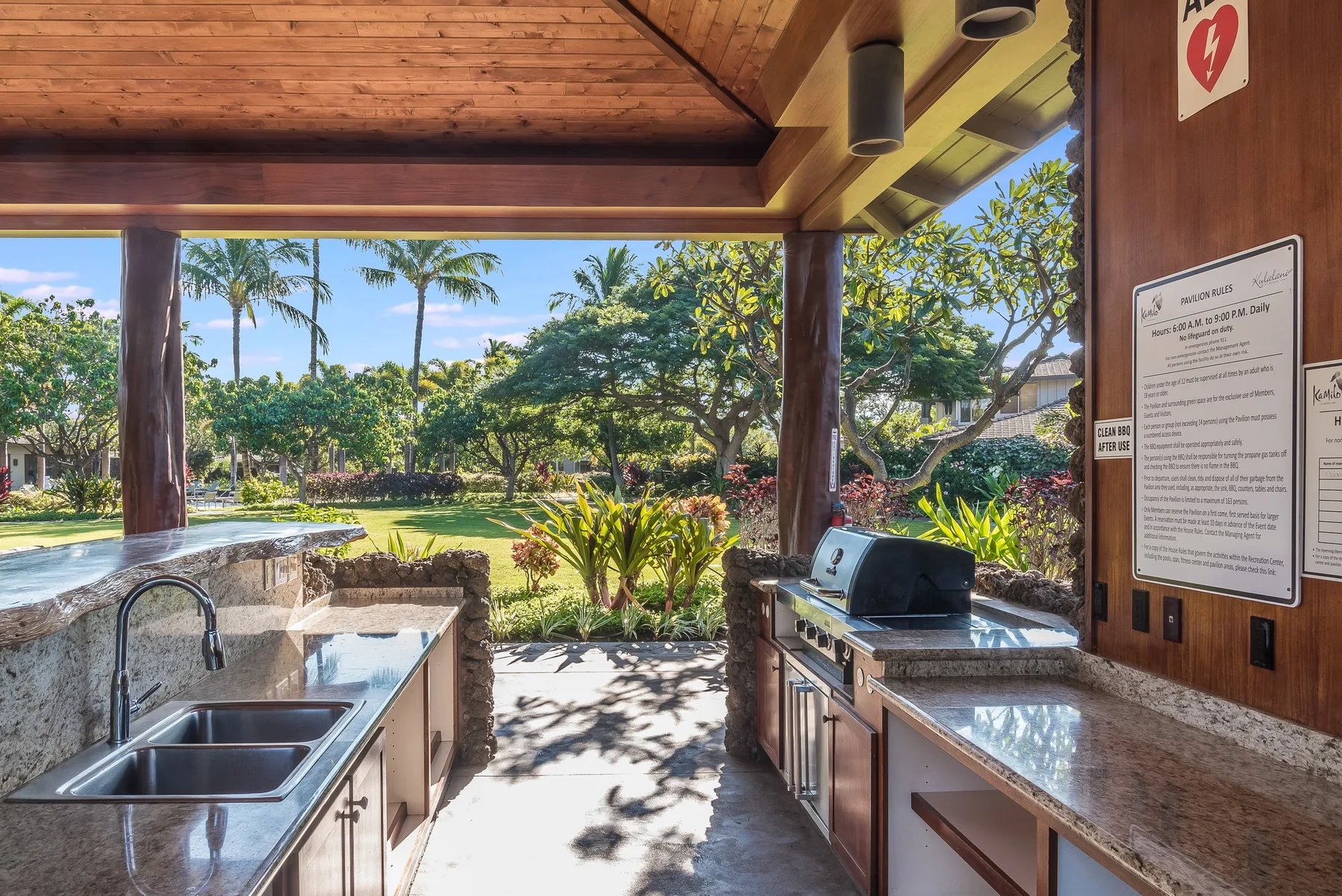 An outdoor kitchen opens onto a garden, with counters and a grill.