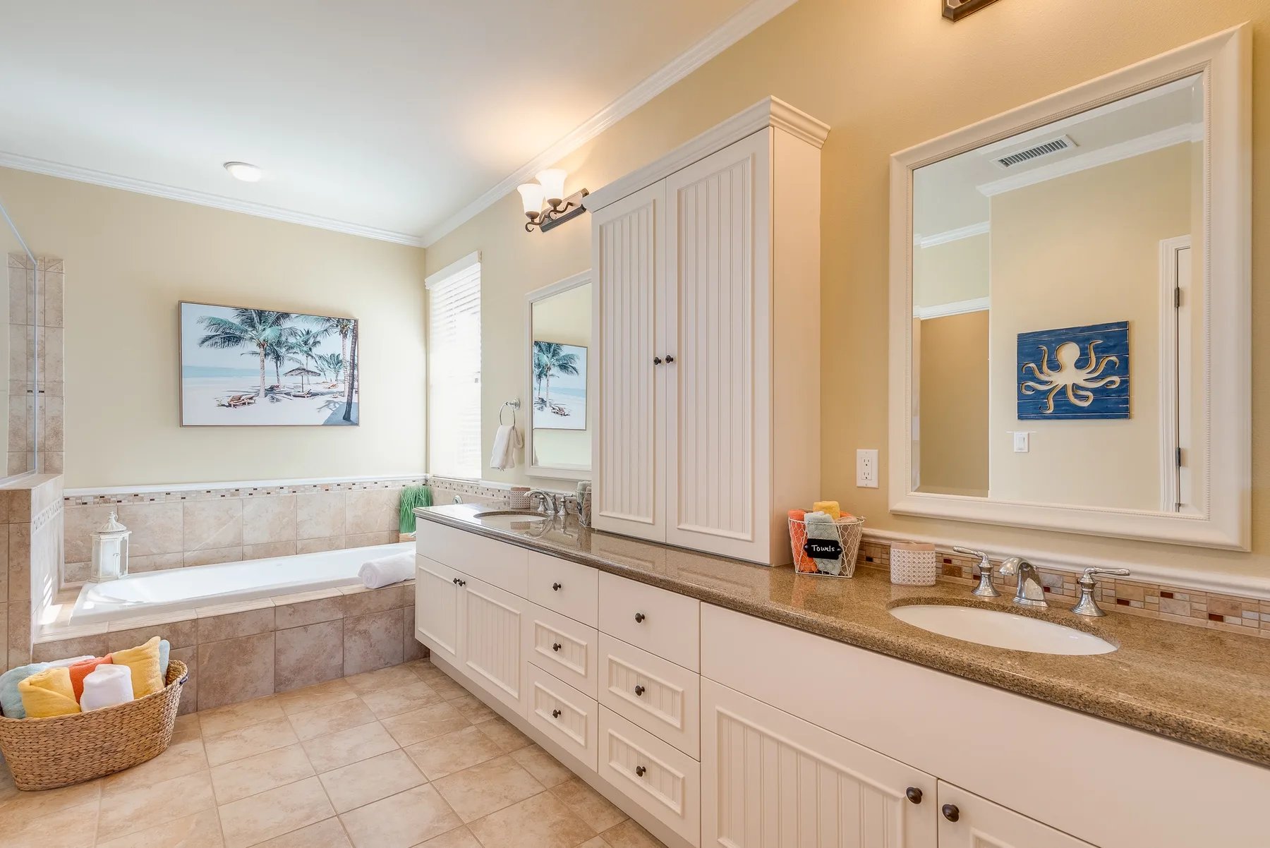 A bright bathroom with a bathtub, vanity, and large wall mirror.