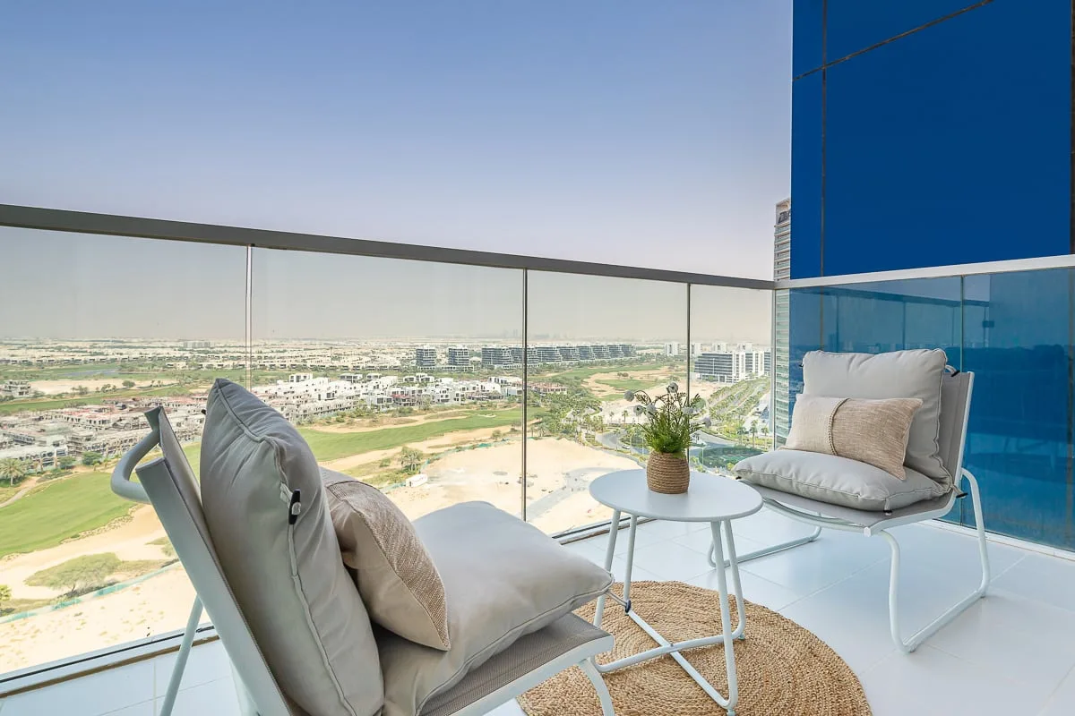 A balcony seating area overlooks a broad landscape, with a small table between the seats.