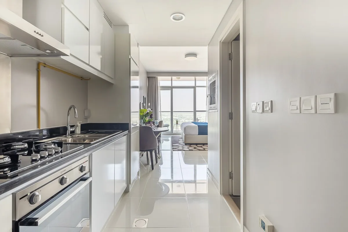A bright kitchen opens into a dining and living area with large windows.