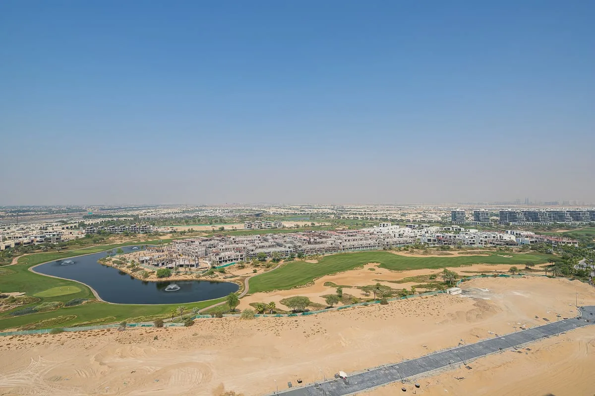 Aerial view of a landscaped development with green spaces and a winding waterway.