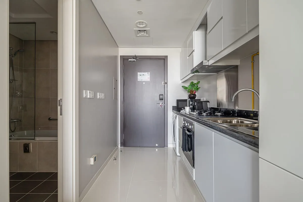 A narrow kitchen with a counter and appliances runs beside a hallway.