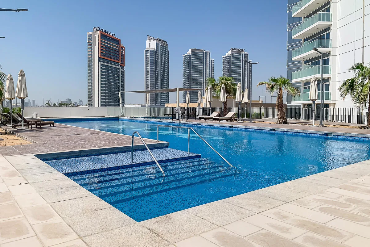 A rooftop swimming pool sits beside lounge seating, with high-rise buildings in the background.
