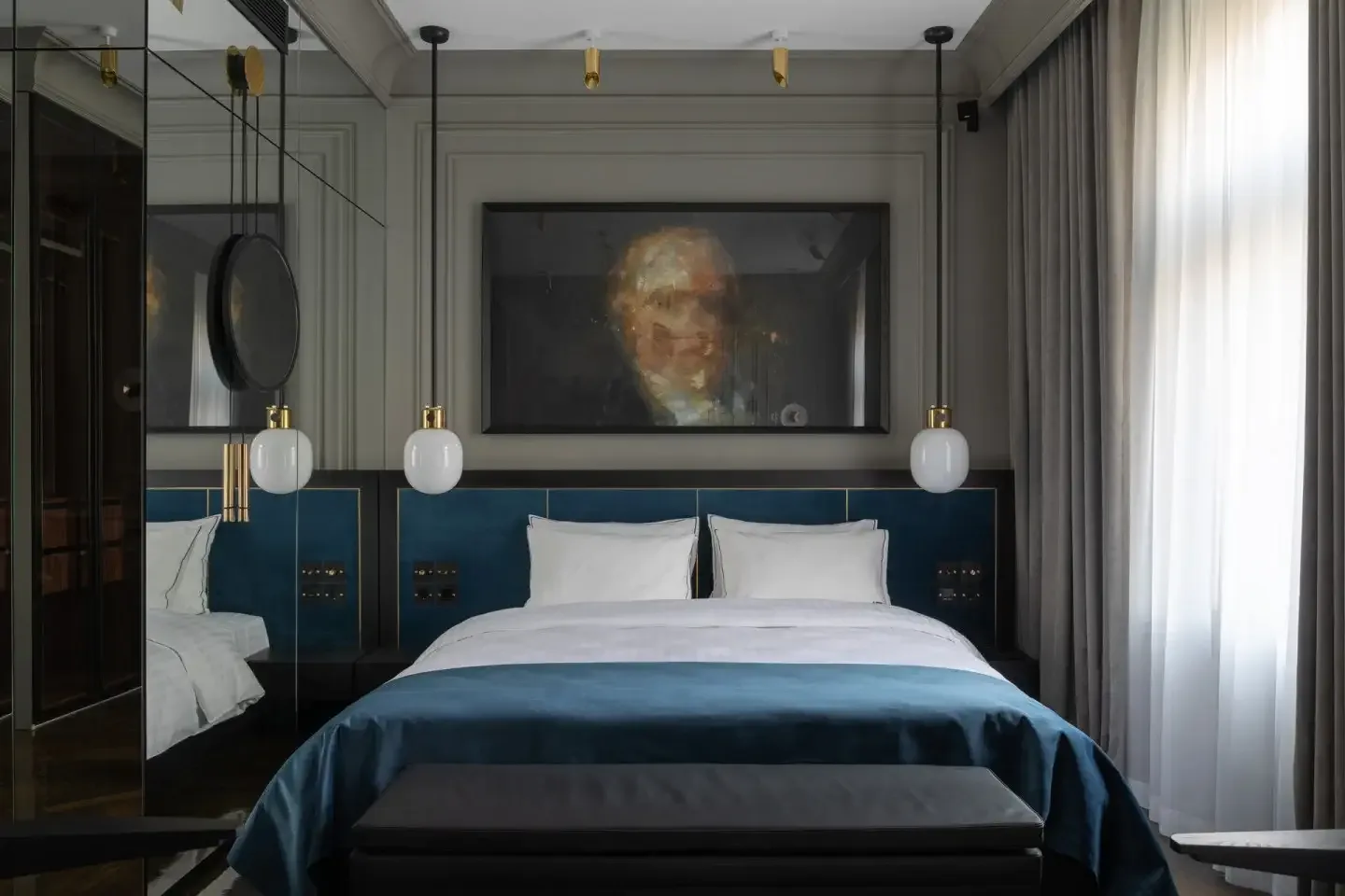 Deluxe Room with blue velvet headboard and portrait artwork