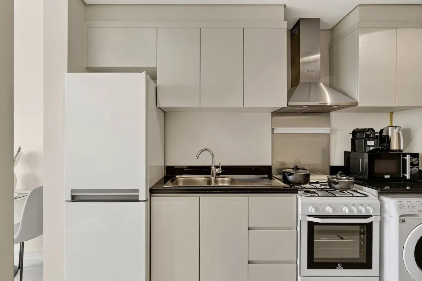 Una cocina moderna con gabinetes blancos, un refrigerador y electrodomésticos.