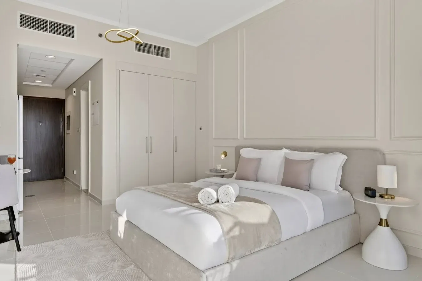 Un dormitorio con una cama bien tendida y un pasillo que conduce a una puerta oscura.
