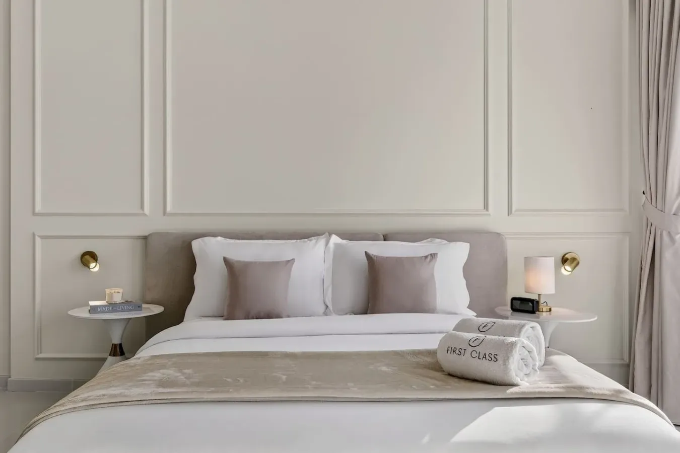 Un dormitorio ordenado muestra una cama con ropa de cama blanca y varias almohadas.
