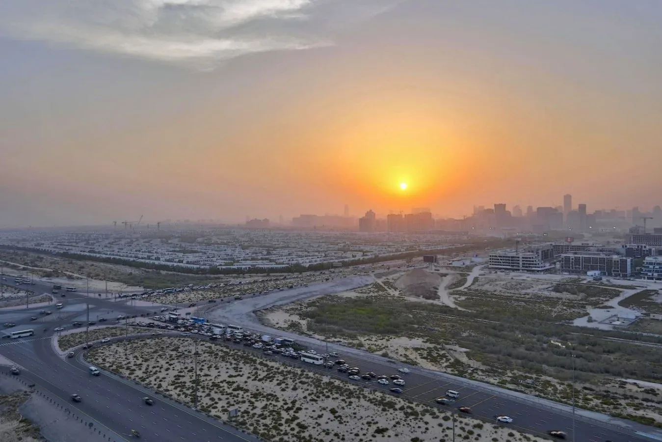 Un atardecer brumoso ilumina el horizonte de la ciudad y sus carreteras.