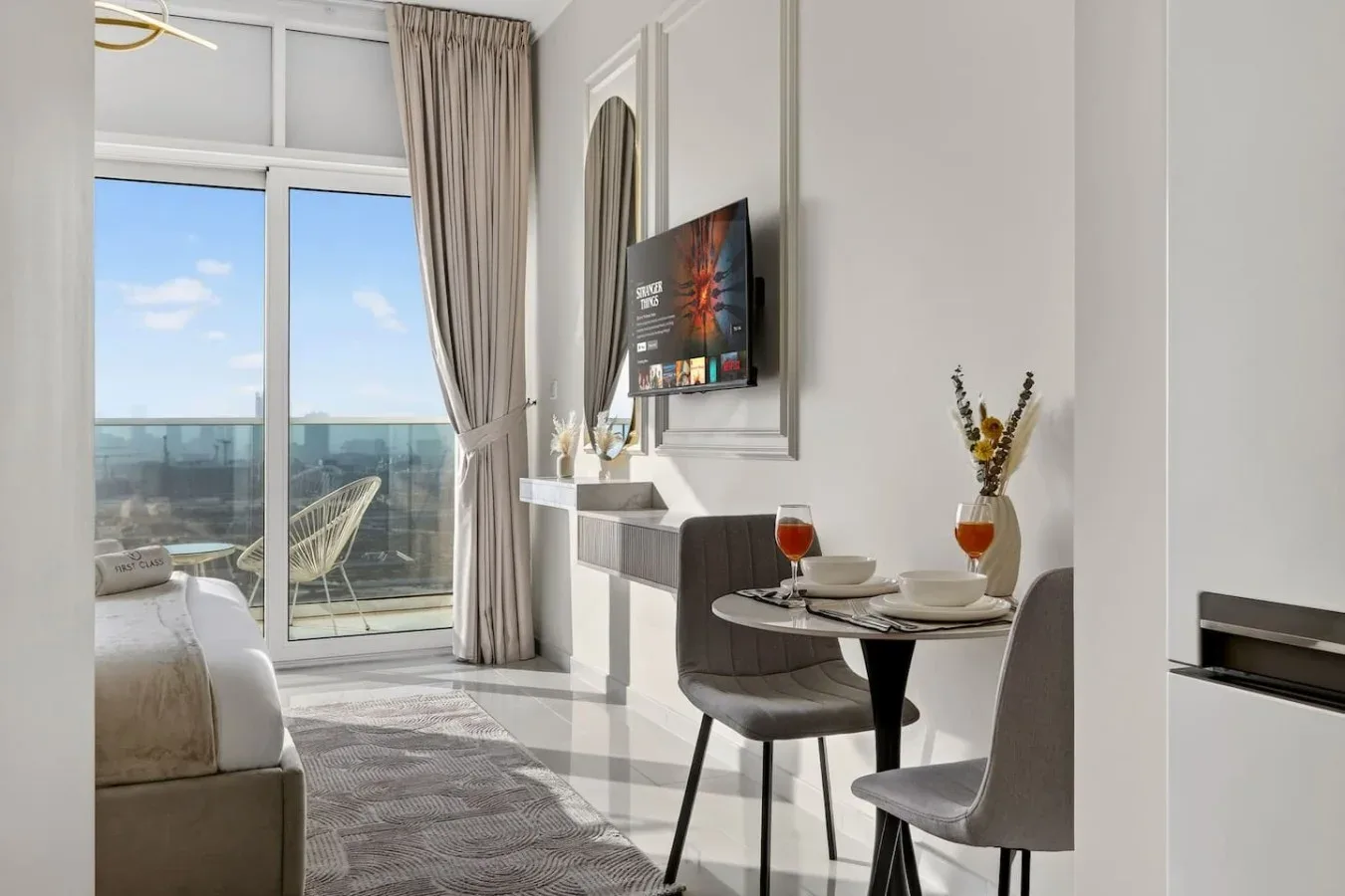 Un luminoso dormitorio tiene una pequeña mesa de comedor junto a una ventana de balcón.