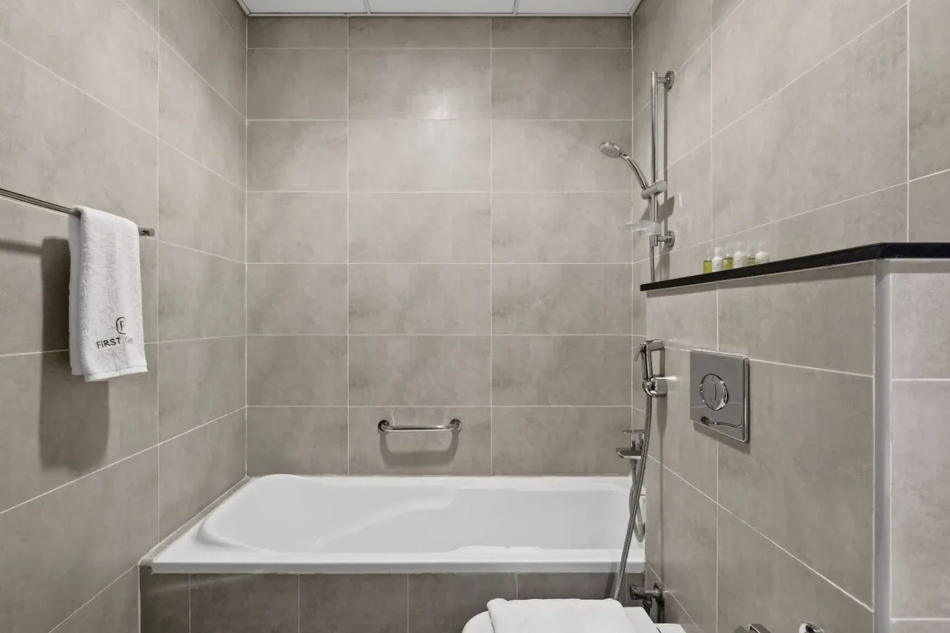 Un baño alicatado con bañera, ducha de mano y toallero.