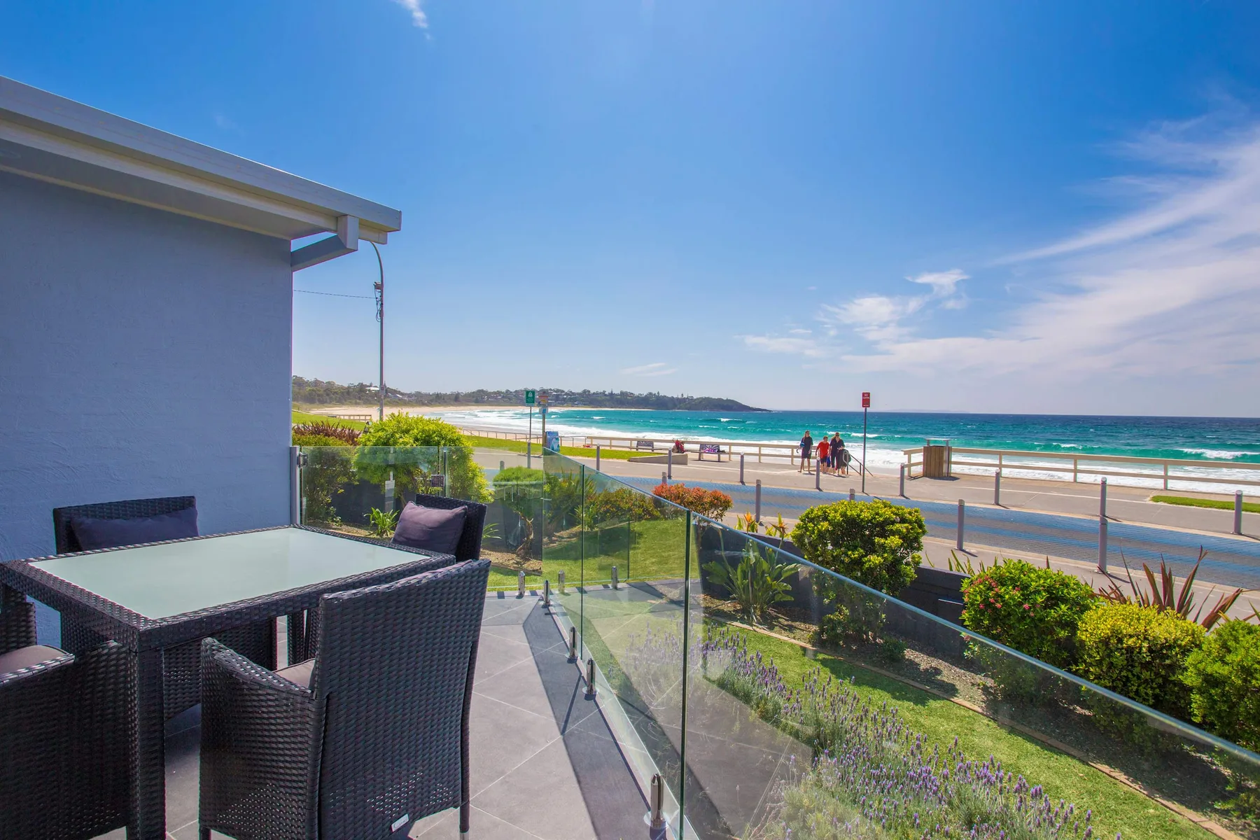 A patio with outdoor seating overlooks a beach and ocean.