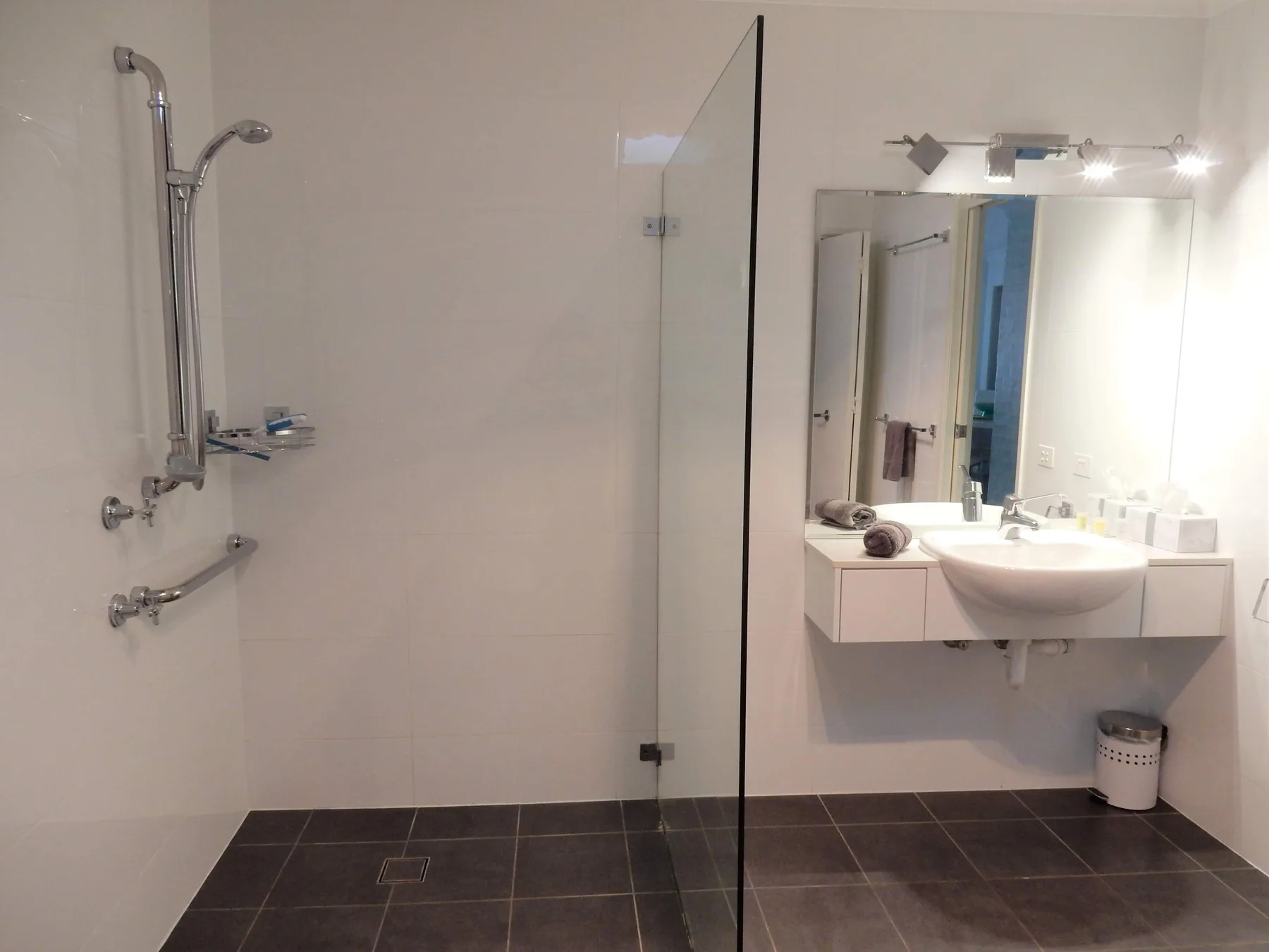 A bathroom with a shower and a sink beneath a mirror.