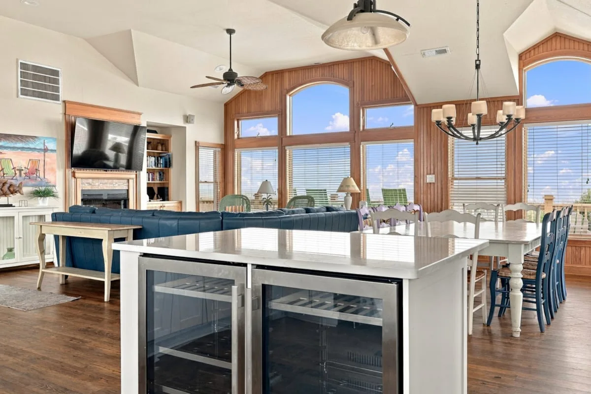 Una luminosa cocina y comedor de planta abierta, con grandes ventanas e isla central.
