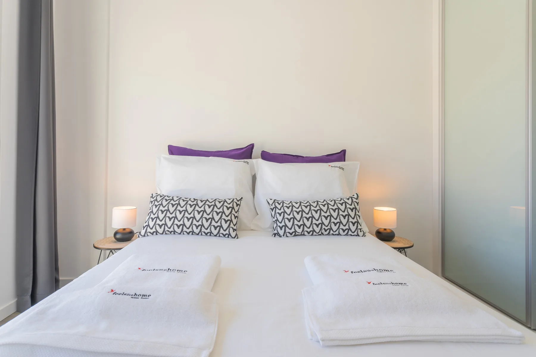 Un dormitorio con una cama bien hecha y lámparas a ambos lados.