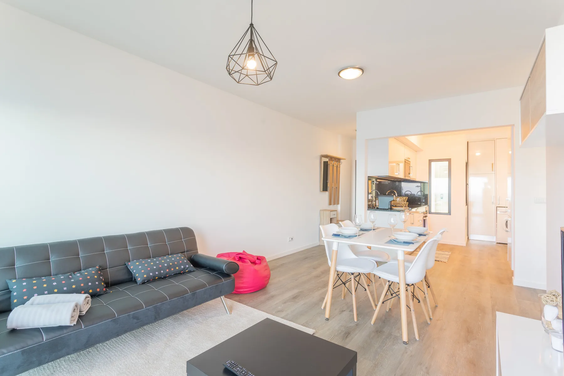 Una zona de estar y comedor con asientos, una mesa y una estancia contigua luminosa.