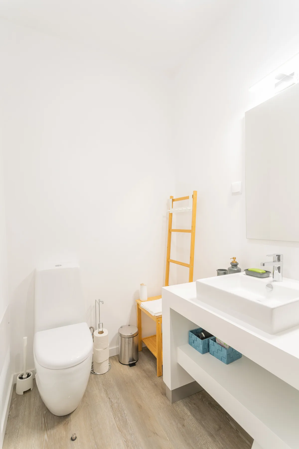 Un baño luminoso con inodoro, lavabo y toallero de madera.