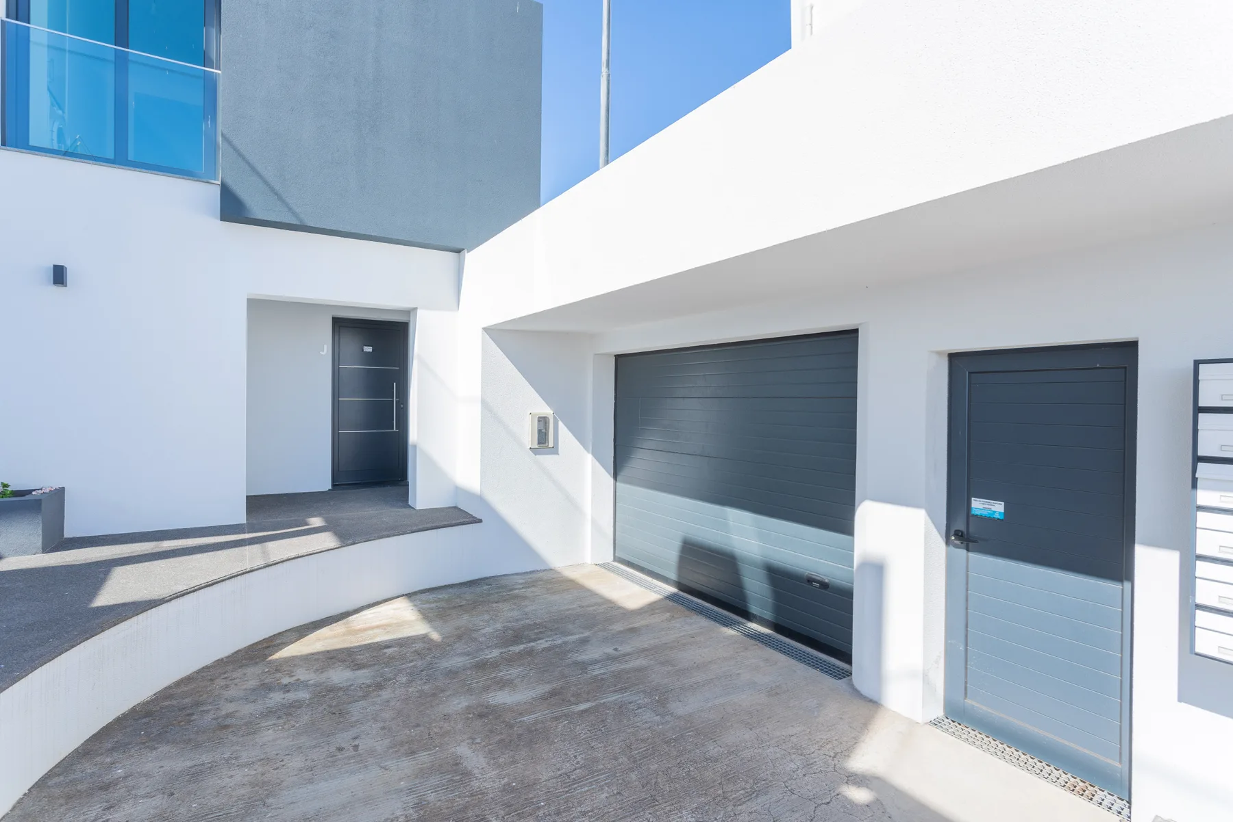 Exterior de un edificio moderno con una puerta de garaje y una entrada independiente.