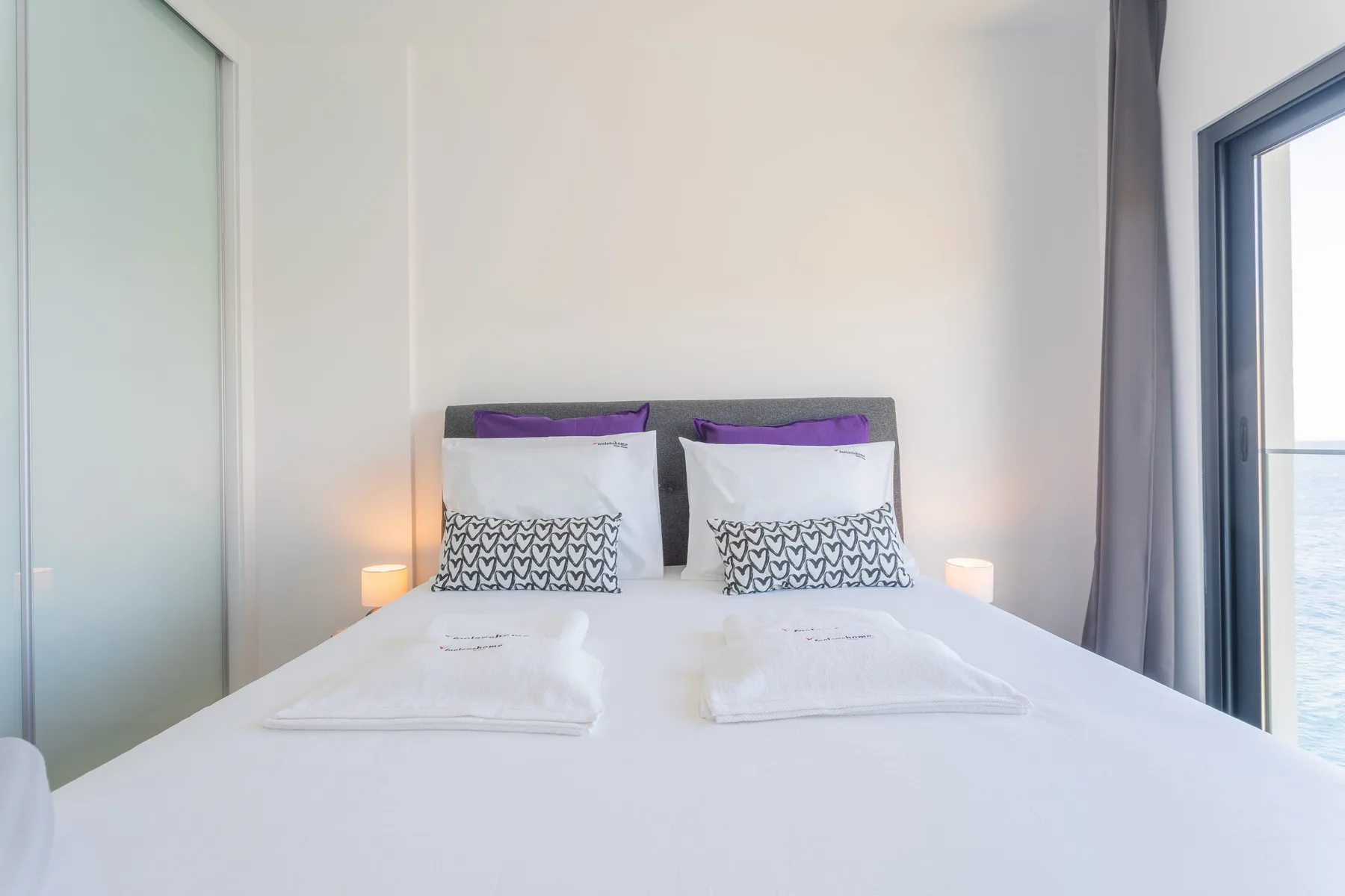 Un dormitorio ordenado con almohadas estampadas y luces junto a la cama.