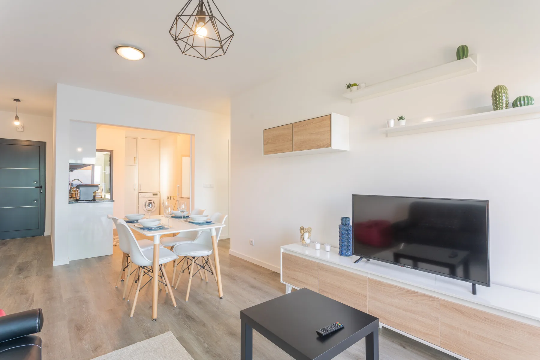 Una luminosa sala de estar y comedor cuenta con un televisor y una mesa con asientos.