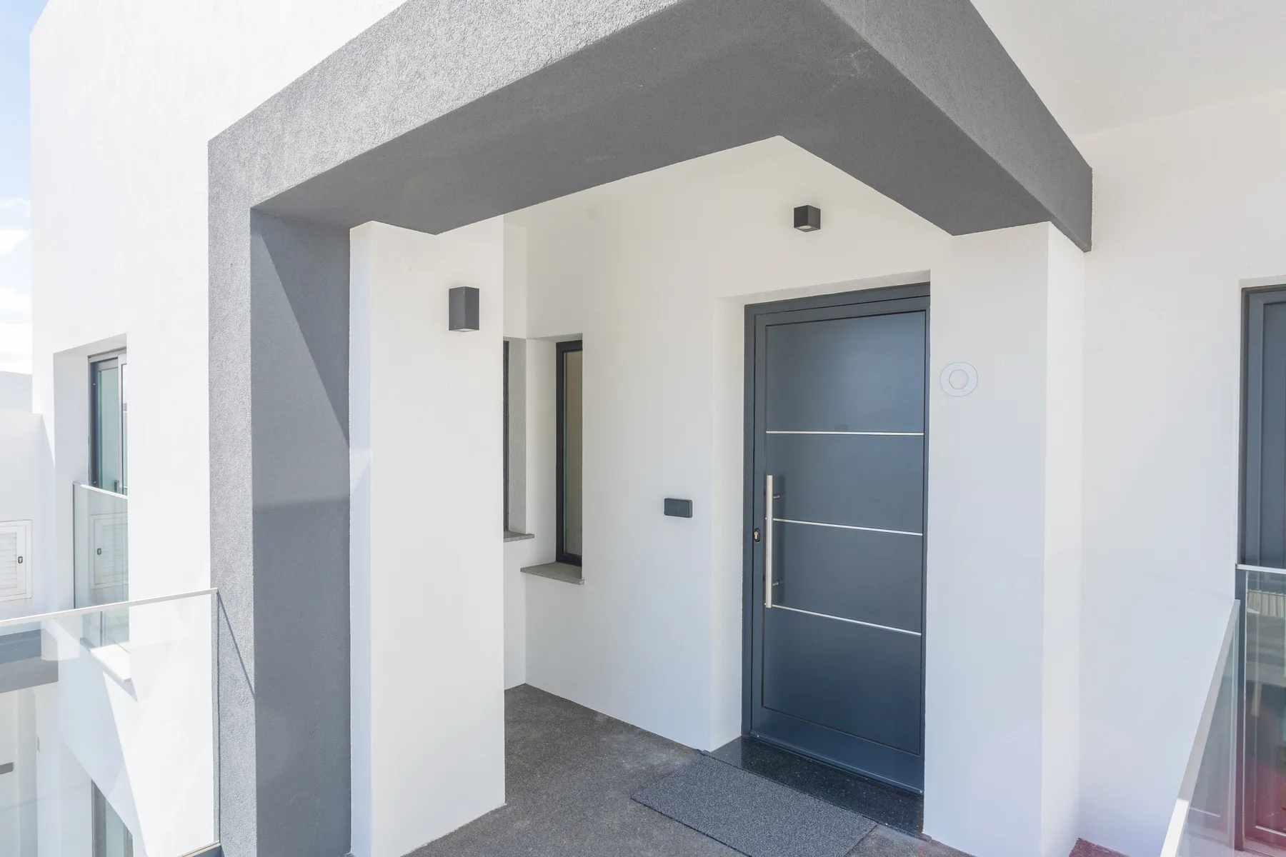 A modern apartment entrance with a dark front door and white walls.