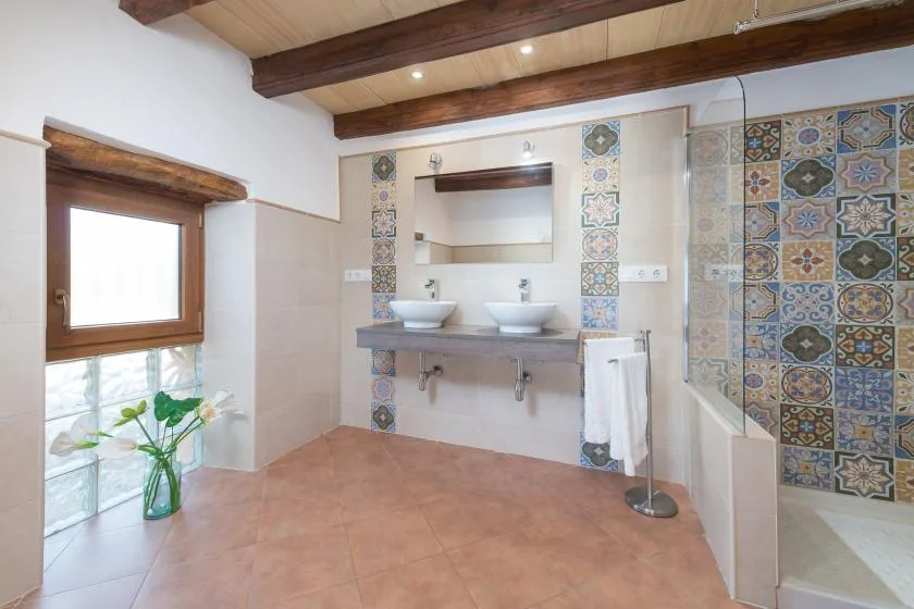 A bathroom with a double vanity, patterned tile, and a glass shower.