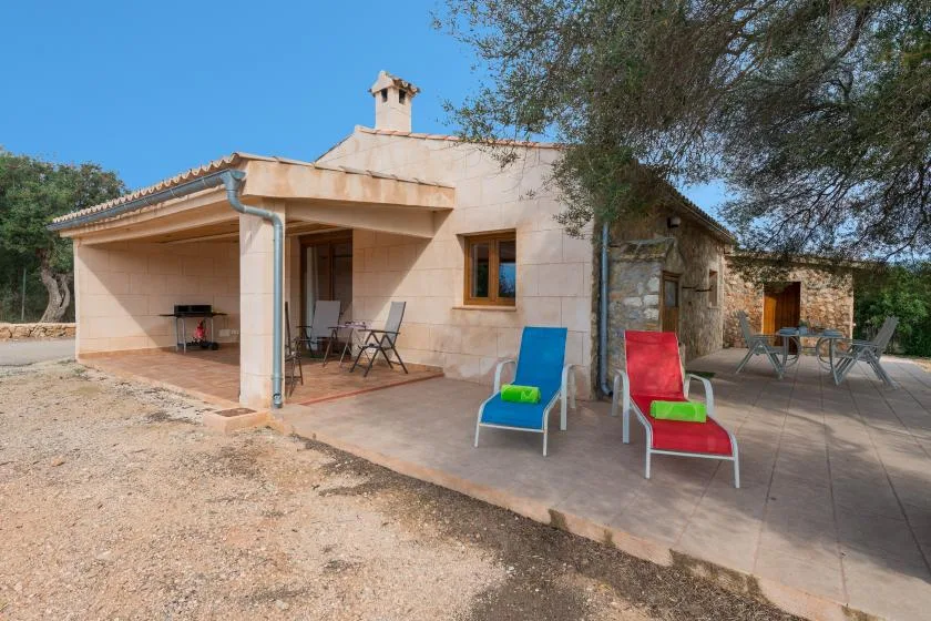 A stone house opens onto a paved patio with outdoor seating.