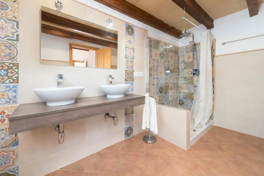 A bathroom with a double-sink vanity and a tiled shower area.