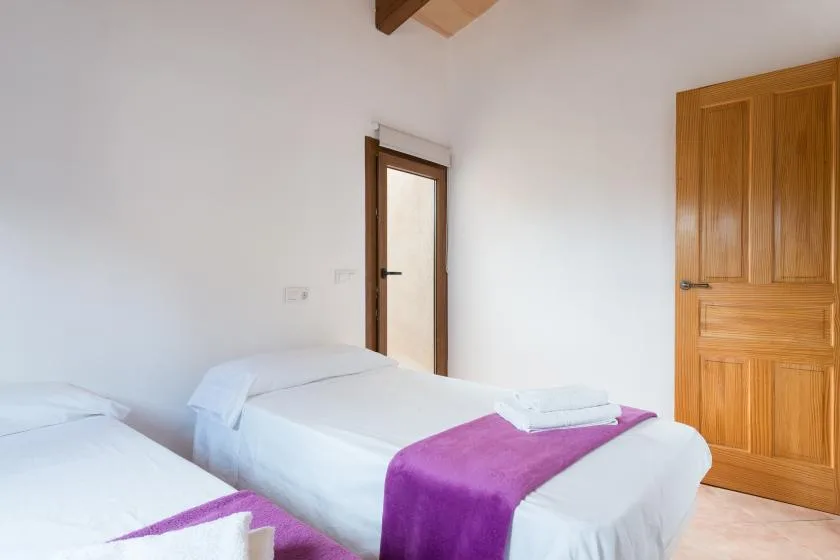 A bedroom with two beds, white bedding, and purple bed runners.