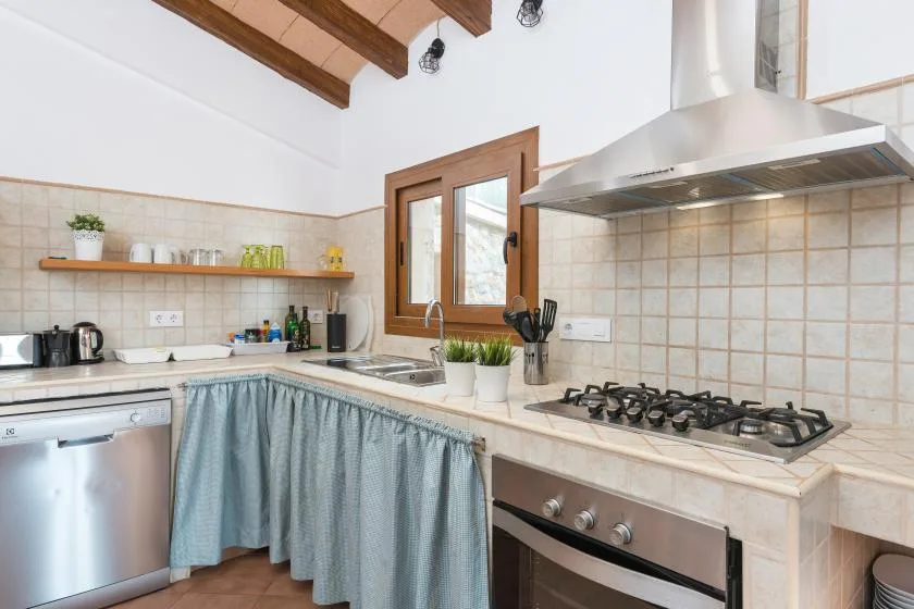 A bright kitchen with tiled counters, a cooktop, and a window.