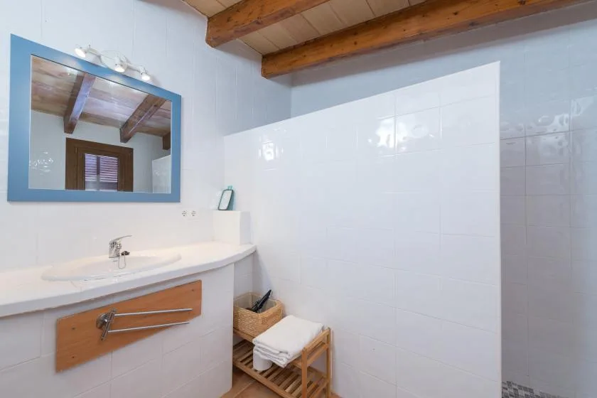 A tiled bathroom vanity with a blue-framed mirror and a towel stand.