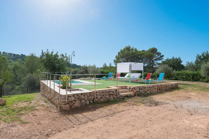 An outdoor pool area with lounge seating and trees in the background.