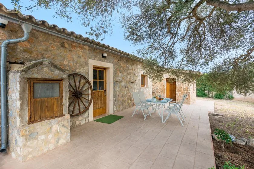 A stone building opens onto a paved patio with outdoor seating.