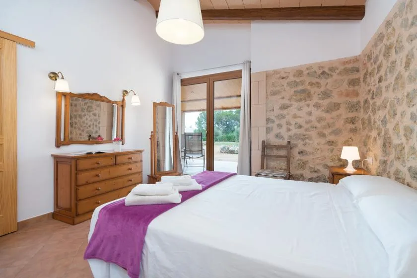A bedroom with a neatly made bed and a wooden dresser.