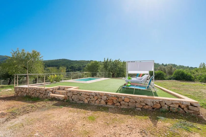 An outdoor swimming pool sits beside lounge seating on a raised lawn.